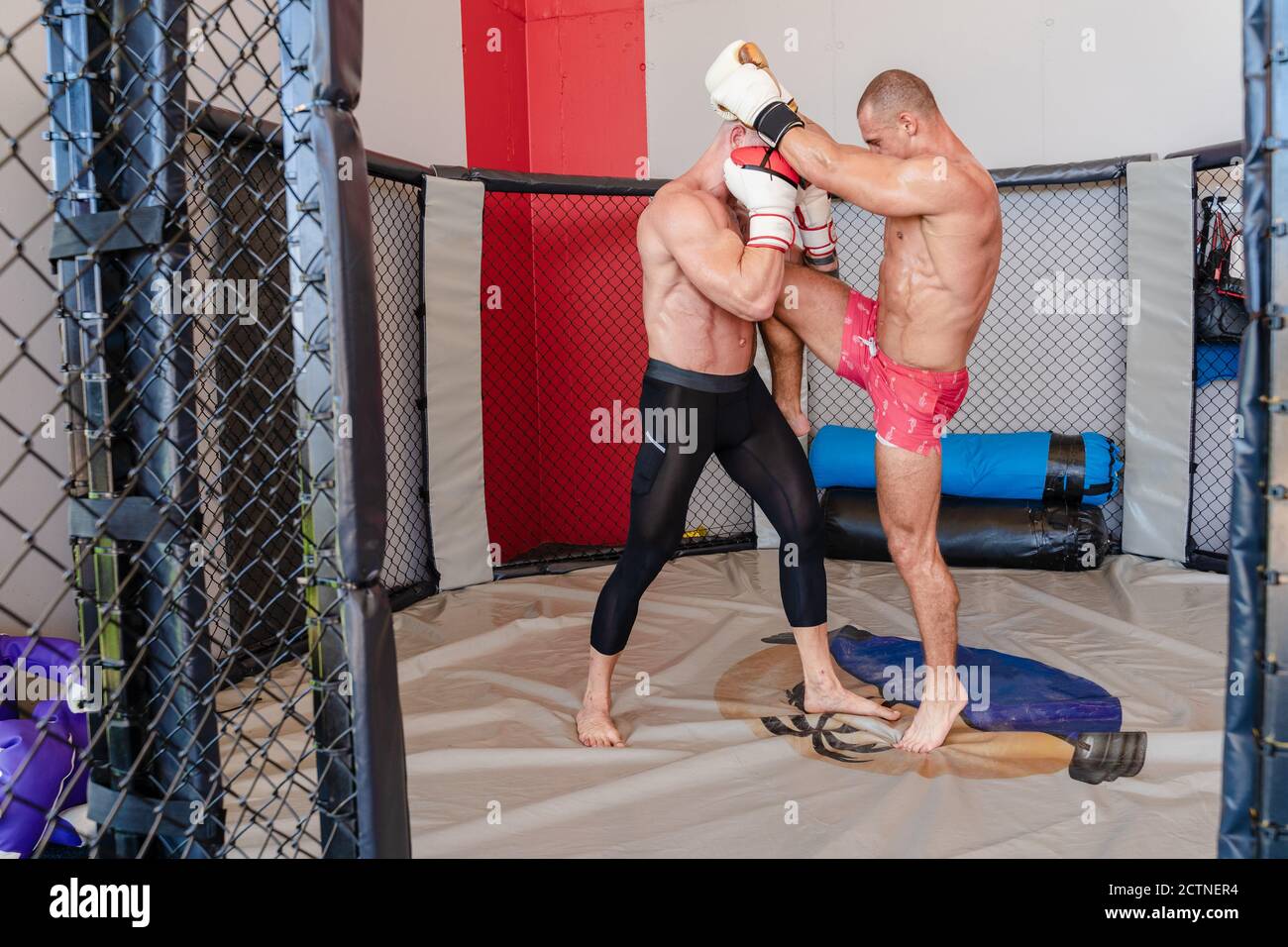 Vue latérale des baskets de pratique de boxer pour homme avec un instructeur fort sur le ring de boxe pendant l'entraînement Banque D'Images