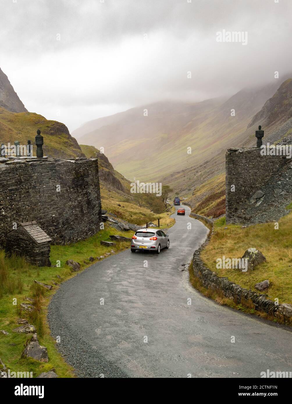 Honister Pass Summit - route pittoresque du col de montagne dans le Lake District, Angleterre Royaume-Uni - voitures passant des sculptures de chaque côté de la route à la mine Honister Slate Banque D'Images