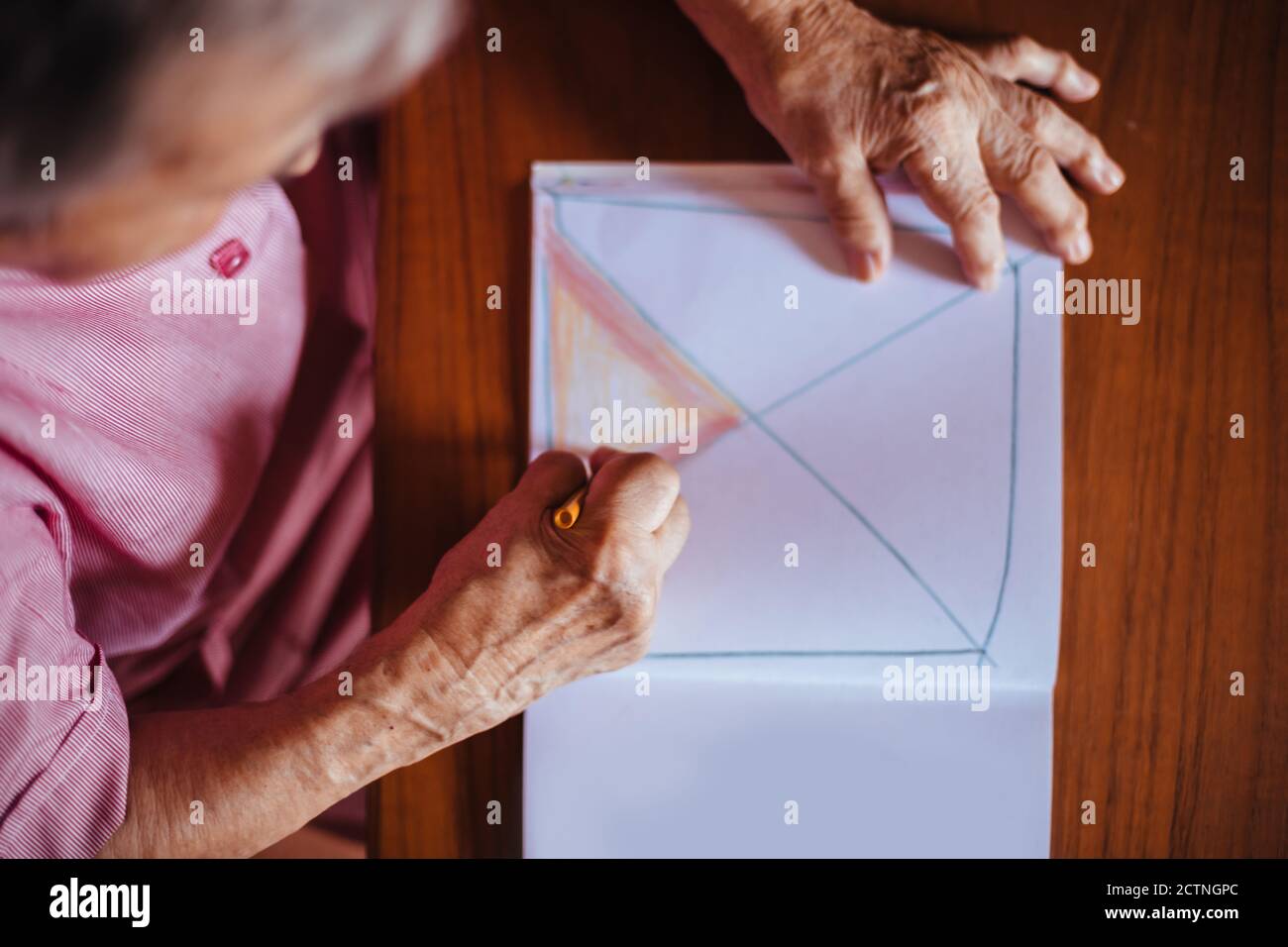 Vue de dessus d'une femme âgée atteinte de problèmes de santé mentale de la maladie d'Alzheimer peint sur un carnet à l'intérieur de sa maison Banque D'Images