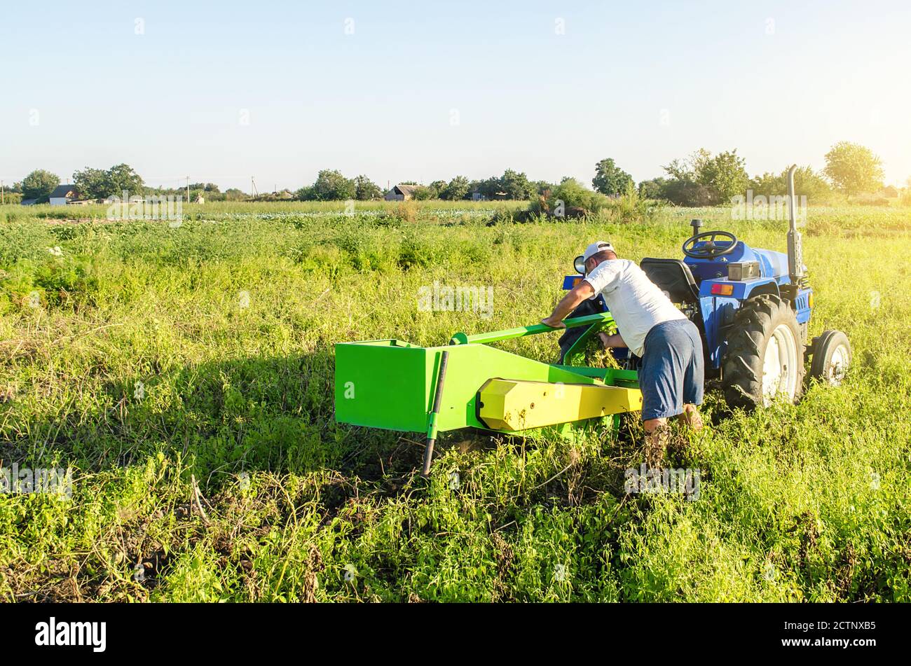 Un agriculteur sert un tracteur sur un champ de plantation agricole. Réparation de la machine de creusement de pommes de terre. Maintenance de l'équipement et des machines. Un petit déjeuner inattendu Banque D'Images