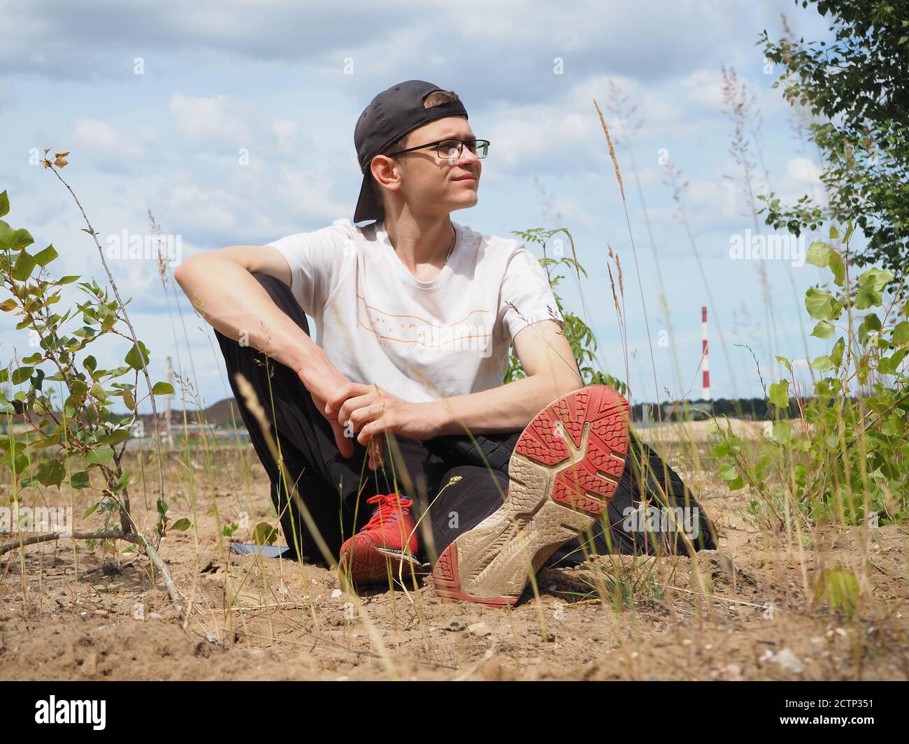 Un jeune homme est assis dans un parc sur le sable. Banque D'Images