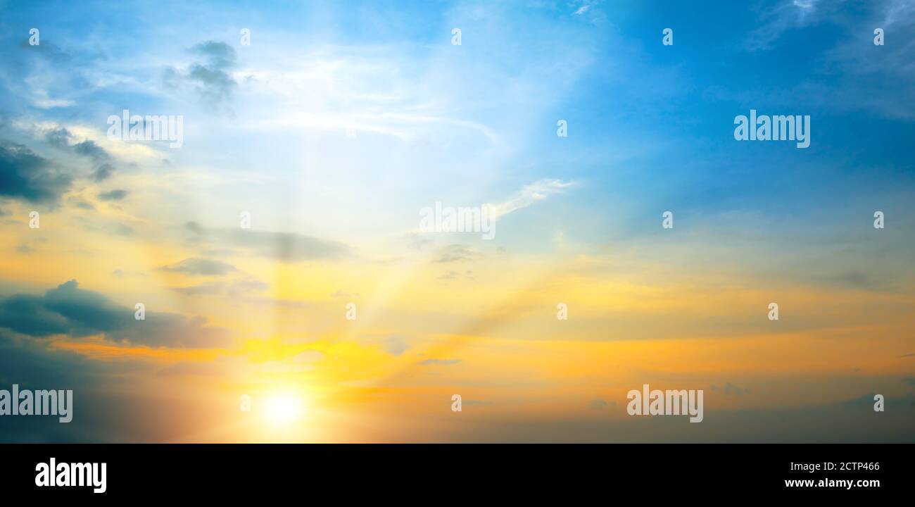 Photo panoramique coucher de soleil de printemps lumineux avec ciel bleu, soleil rouge et rayons de soleil. Banque D'Images