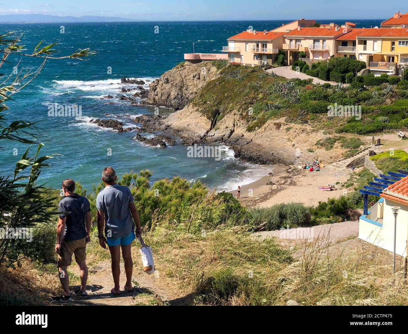 Vacanciers sur une petite plage près des falaises de la mer Méditerranée à Collioure, France. Derrière se trouvent des maisons de vacances avec des toits de tuiles rouges. Banque D'Images