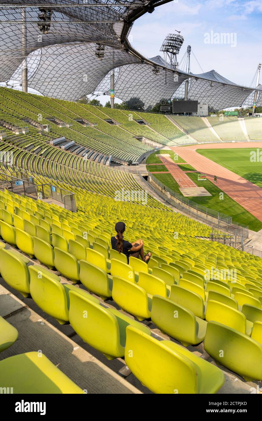 Munich, Bavière / Allemagne - 17 septembre 2020 : une seule femme aux longs cheveux bruns assise seule dans un stade géant et vide Banque D'Images