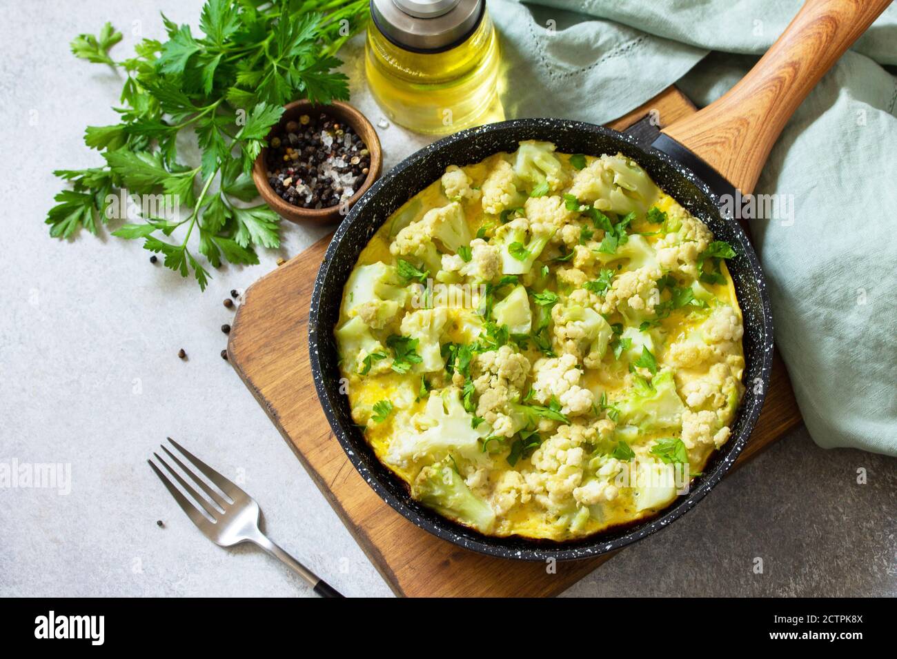 Petit déjeuner sain ou déjeuner diététique. Omelette aux œufs avec chou-fleur dans une casserole en fonte sur une table en pierre légère. Copier l'espace. Banque D'Images