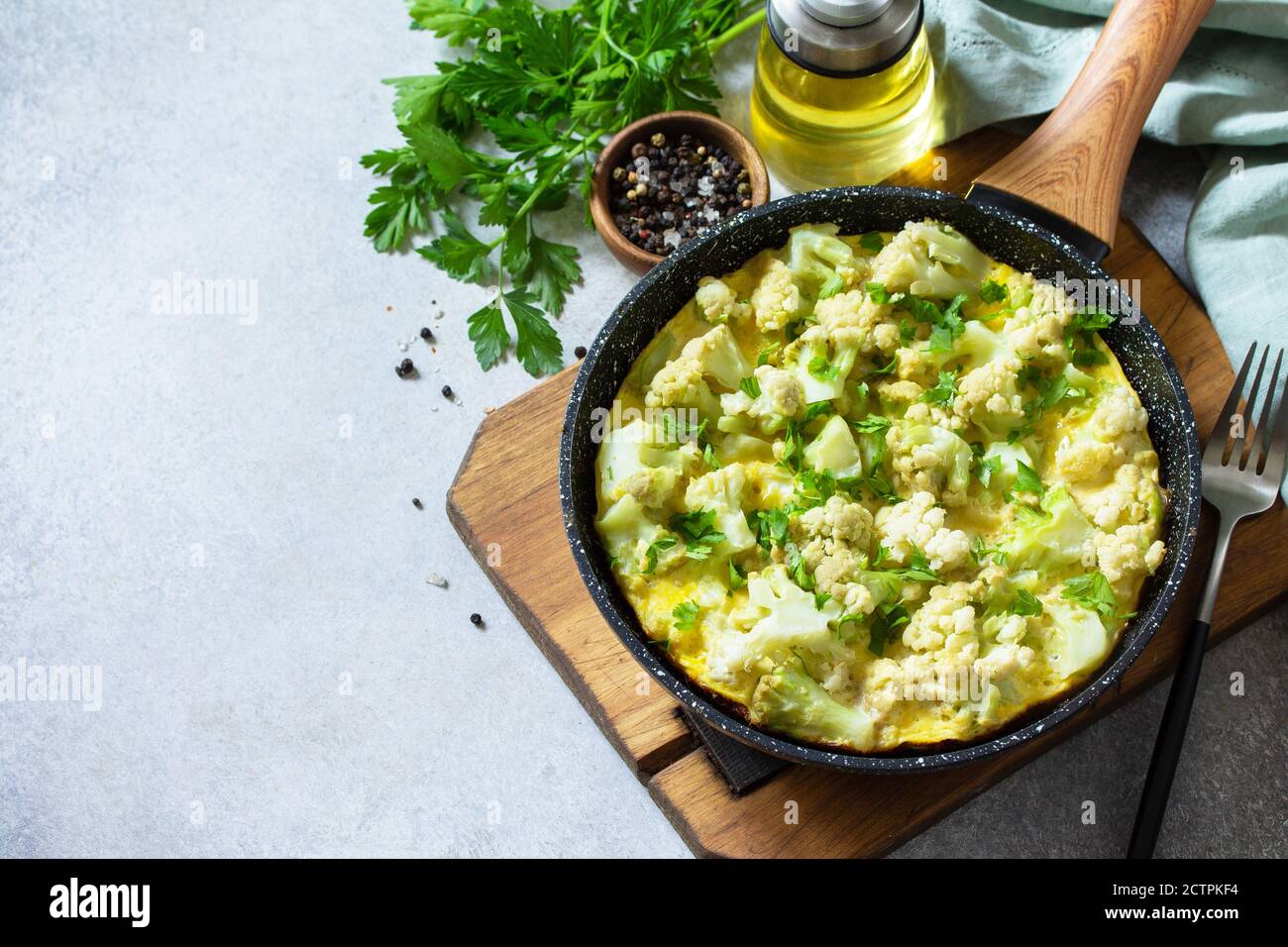 Petit déjeuner sain ou déjeuner diététique. Omelette aux œufs avec chou-fleur dans une casserole en fonte sur une table en pierre légère. Copier l'espace. Banque D'Images