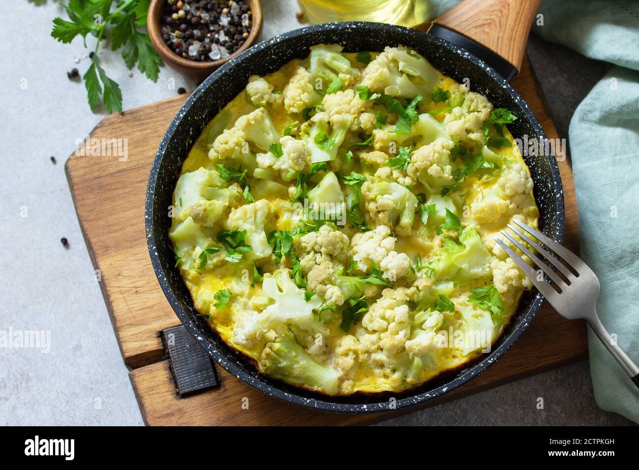 Petit déjeuner sain ou déjeuner diététique. Omelette aux œufs avec chou-fleur dans une casserole en fonte sur une table en pierre légère. Banque D'Images