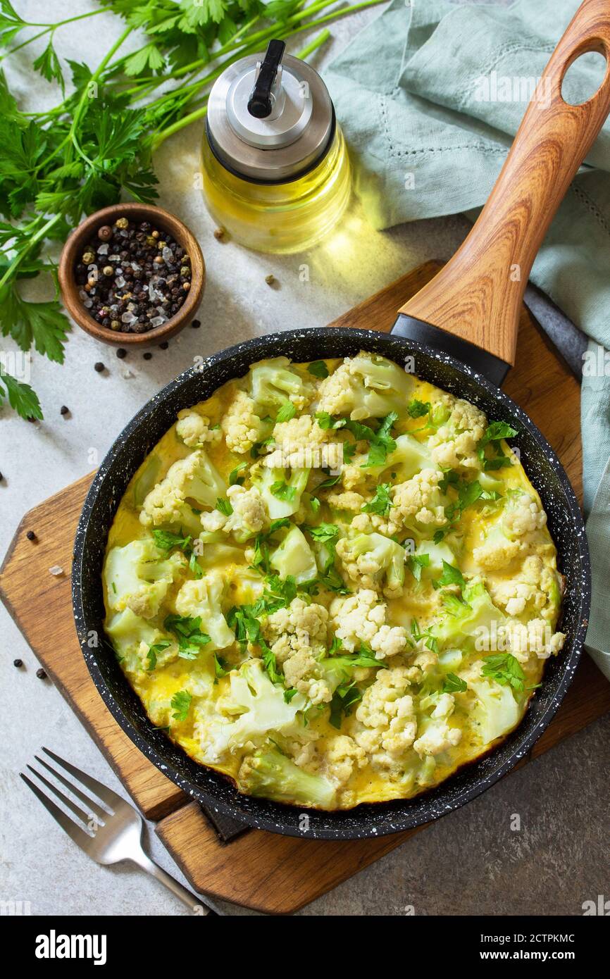 Petit déjeuner sain ou déjeuner diététique. Omelette aux œufs avec chou-fleur dans une casserole en fonte sur une table en pierre légère. Banque D'Images