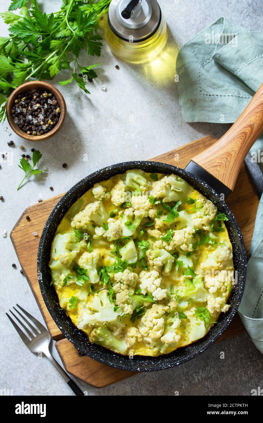 Petit déjeuner sain ou déjeuner diététique. Omelette aux œufs avec chou-fleur dans une casserole en fonte sur une table en pierre légère. Banque D'Images