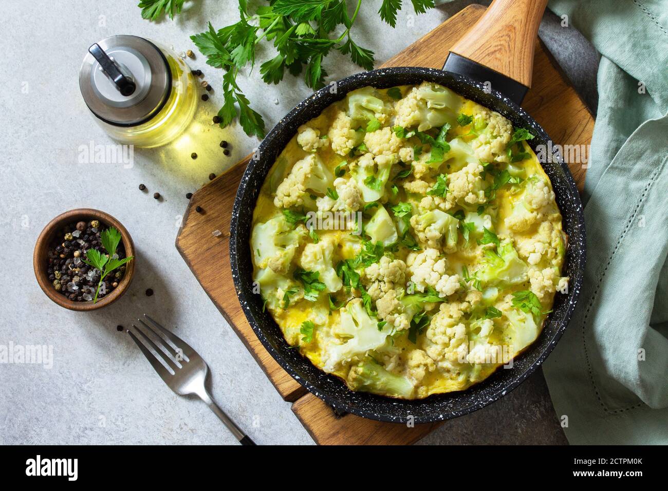 Petit déjeuner sain ou déjeuner diététique. Omelette aux œufs avec chou-fleur dans une casserole en fonte sur une table en pierre légère. Vue de dessus de la pose à plat. Banque D'Images