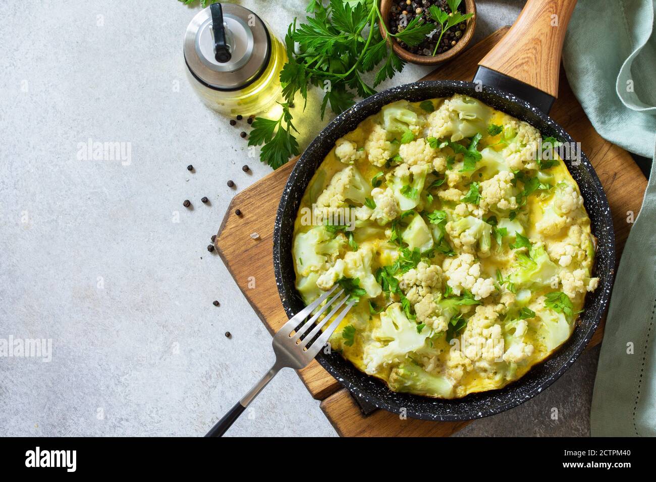 Petit déjeuner sain ou déjeuner diététique. Omelette aux œufs avec chou-fleur dans une casserole en fonte sur une table en pierre légère. Vue de dessus de la pose à plat. Copier l'espace. Banque D'Images