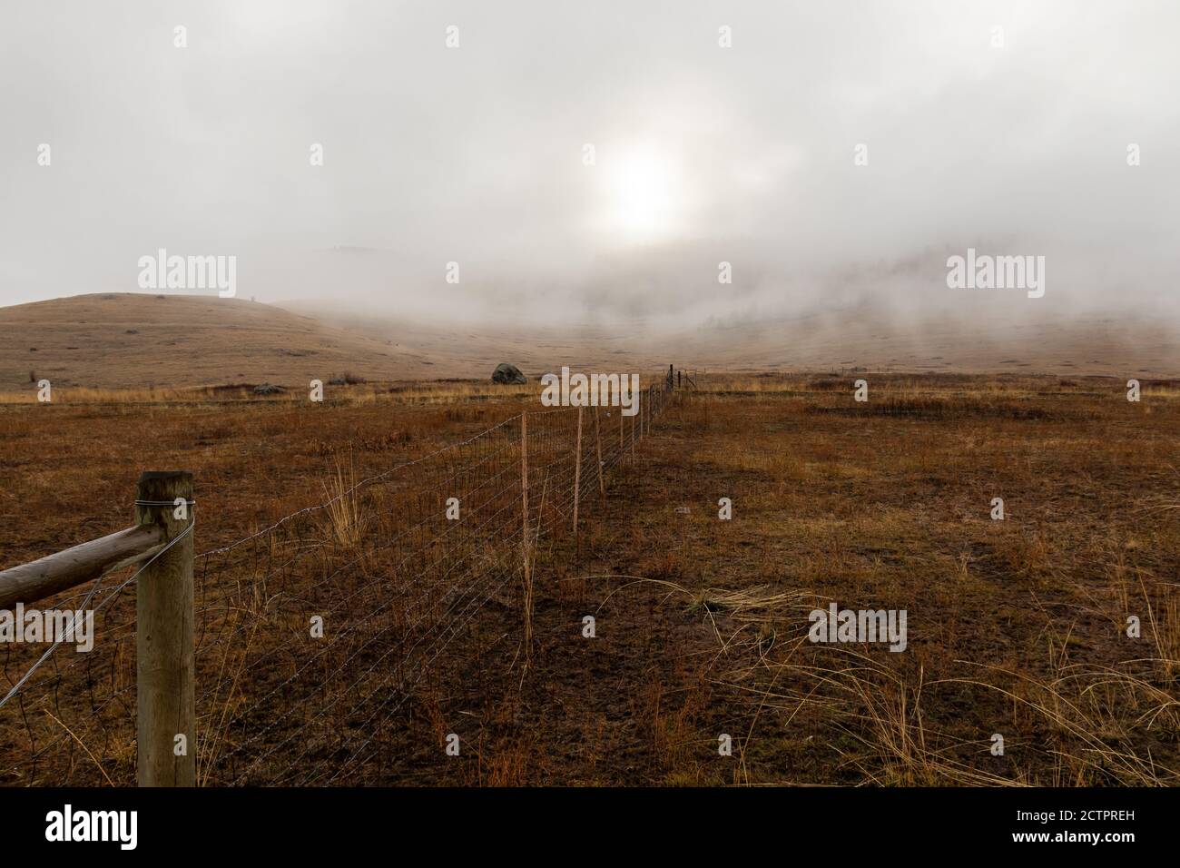 Une vieille clôture traverse un paysage hivernal de rêve, de brouillard, vide et aride au refuge de la faune de la National Bison Range, Montana, États-Unis Banque D'Images