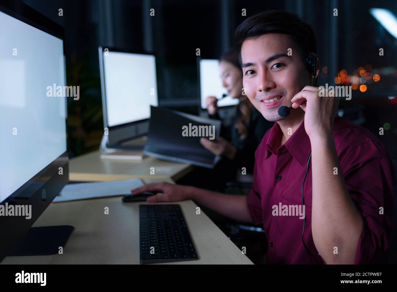 Homme thaïlandais asiatique services à la clientèle les opérateurs de service de nuit dans le centre d'appel pour aider le client d'assistance sur le lieu de travail à l'heure de nuit, amical Banque D'Images