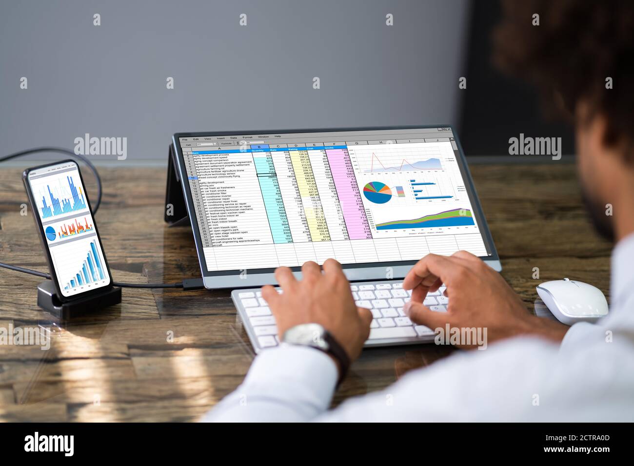 Analyste employé utilisant le logiciel de feuille de calcul sur téléphone avec écran externe Banque D'Images