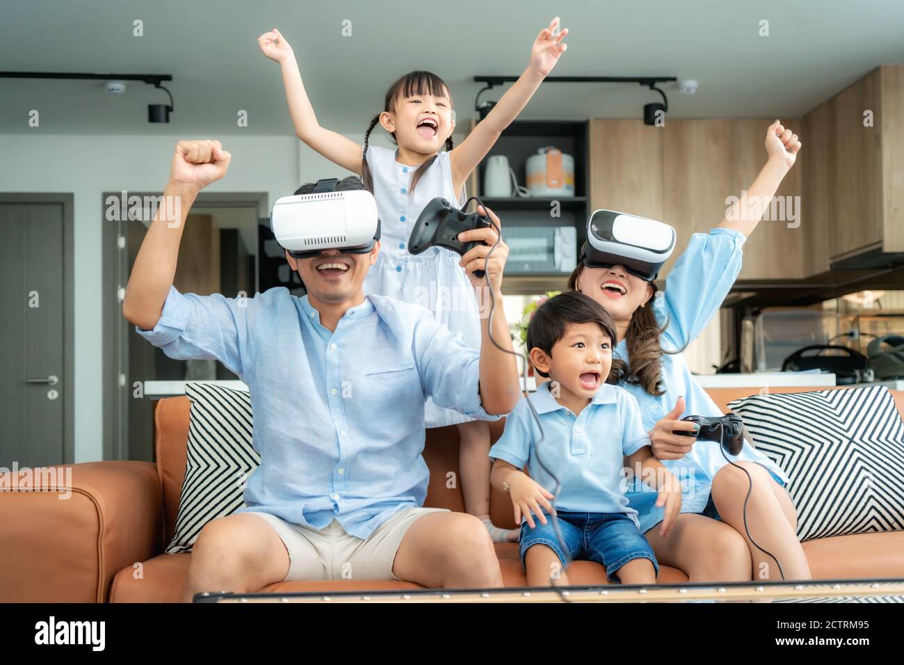 Bonne famille asiatique à la maison sur le salon canapé avoir s'amuser pendant qu'ils regardent la mère et le père jouant des jeux Utilisation du casque de réalité virtuelle VR dans l Banque D'Images