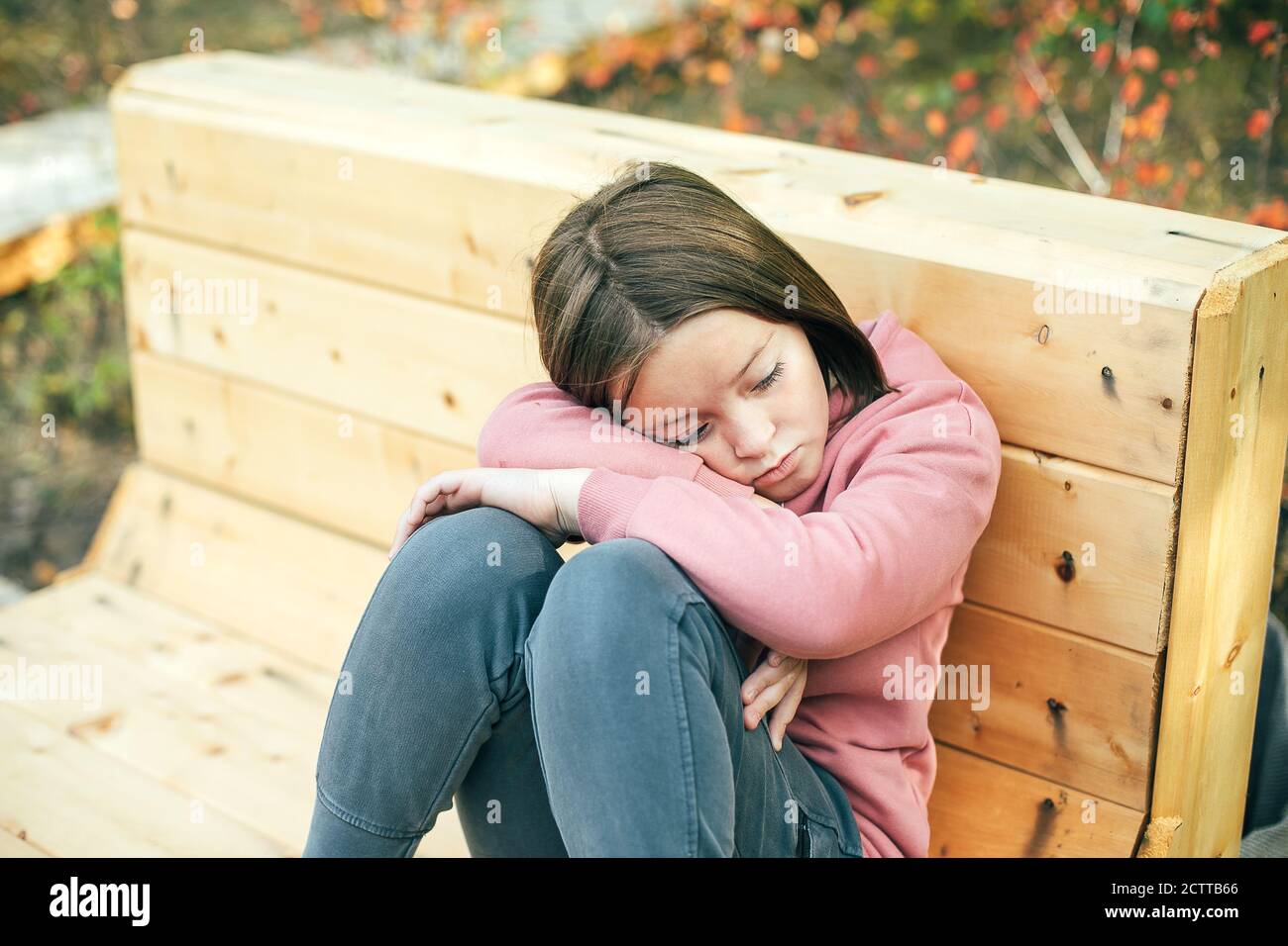 Portrait d'une fille triste et ennuyeuse de 7-8 ans dans un parc de la ville Banque D'Images