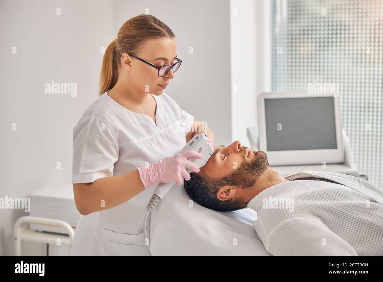 Femme cosmetologiste charmante nettoyant le visage de l'homme avec l'appareil  laser IPL Photo Stock - Alamy