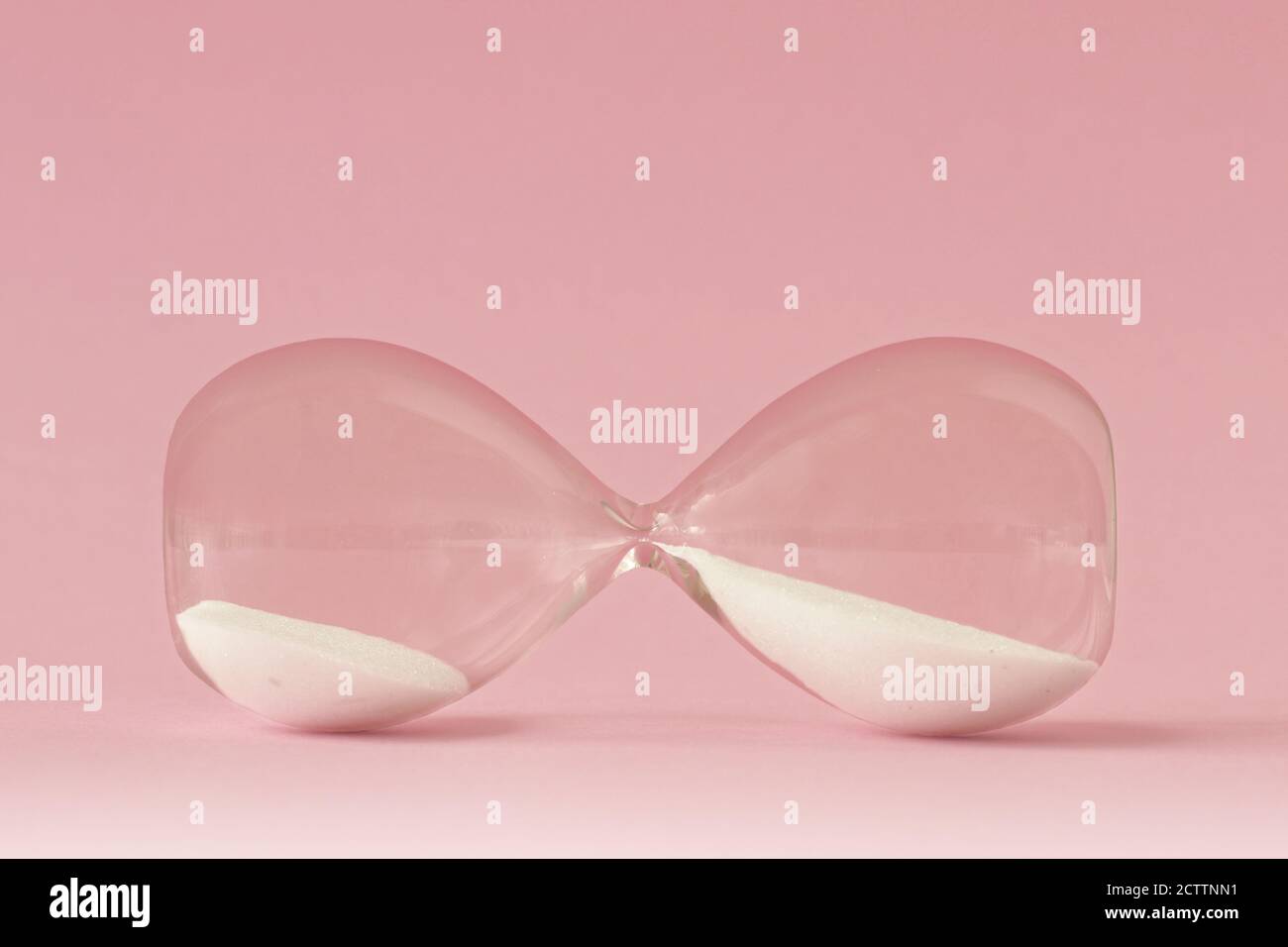 HourGlass couché sur fond rose - concept de temps et femme Banque D'Images