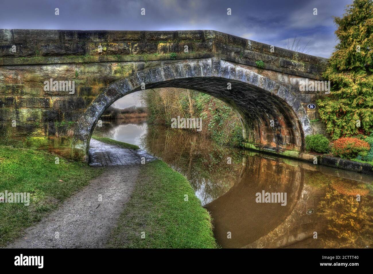 Pont en pierre typique britannique datant de 18 ans sur le canal voûté Canal de Lancaster montrant le chemin de remorquage et la réflexion semi-circulaire dans le STILL eau Banque D'Images