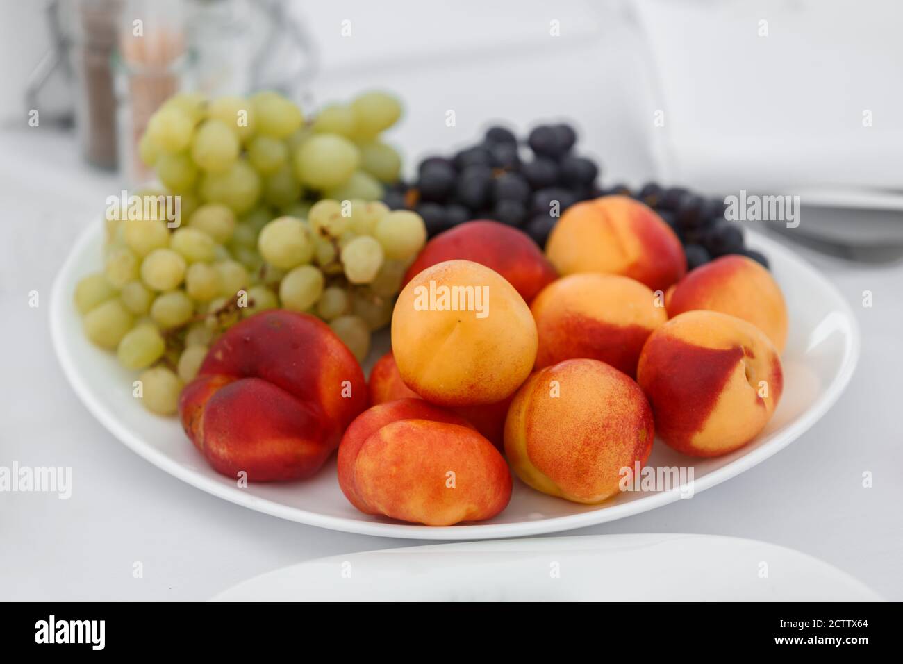 Les pêches sont mûres et les raisins sont sur un plateau. Fragment de paramètre de table Banque D'Images