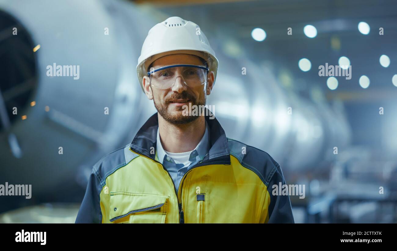 Portrait d'un professionnel souriant, ingénieur de l'industrie lourde, travailleur portant un uniforme de sécurité, des lunettes et un casque de sécurité. Dans la zone arrière-plan non focalisé large Banque D'Images