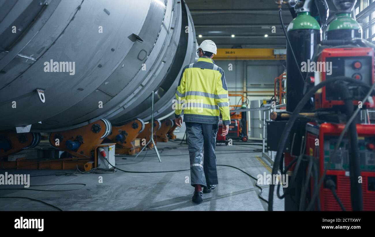 Voici la photo d'un ingénieur de l'industrie lourde qui traverse l'usine de fabrication de tuyaux. Installation moderne pour la conception et la construction de grands diamètres Banque D'Images