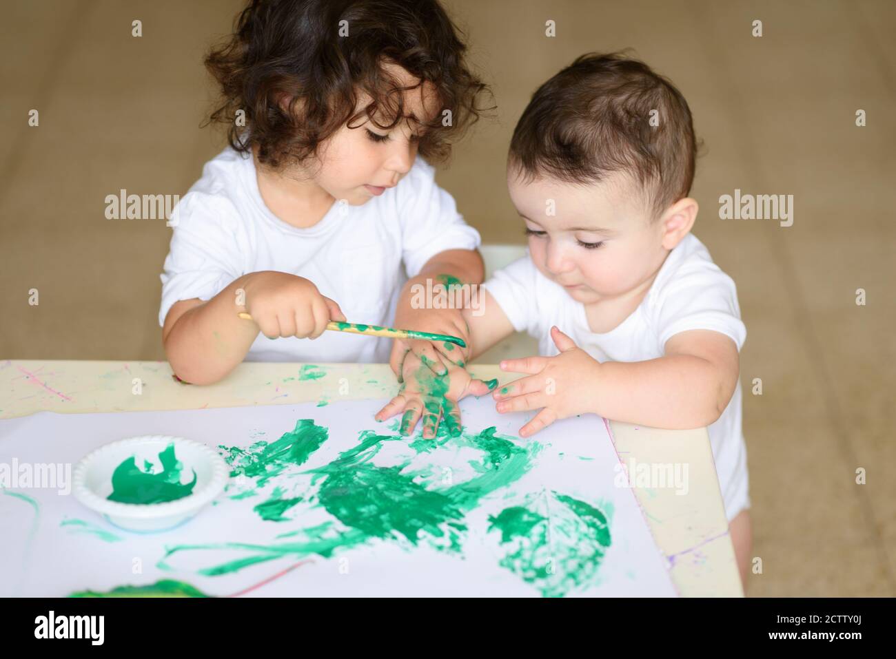 Joli Petit Enfant Fille Et Bebe Garcon Dessin Avec Peinture Vert Aquarelle Et Brosse Sur Les Mains Enfant Mauriquement Adorable Enfants Brunette Peinture A La Table Photo Stock Alamy