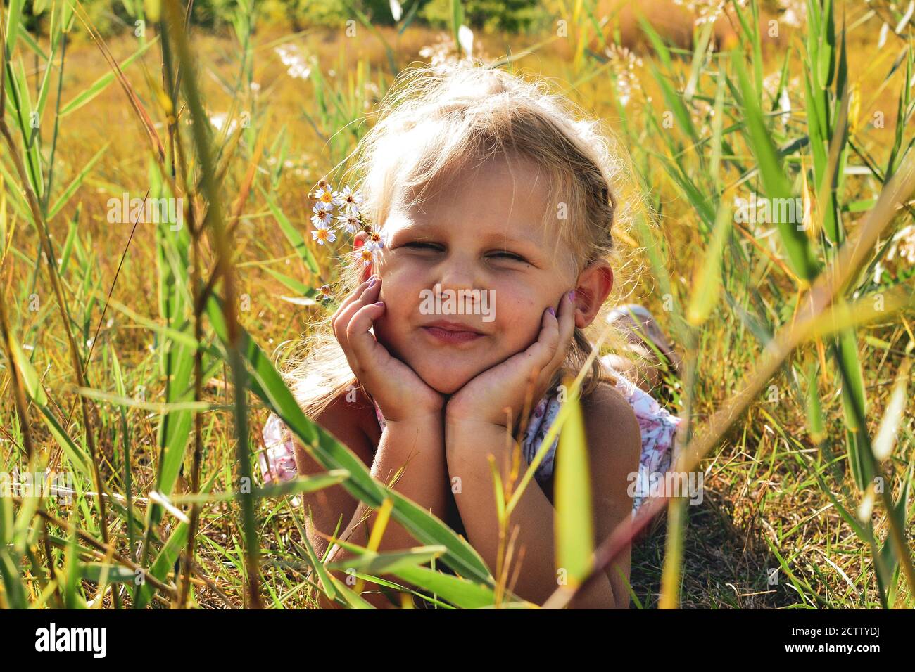 Portrait d'un bébé mignon et beau. L'enfant est dans l'herbe et regarde la caméra. Les moments d'enfance d'été dans la nature Banque D'Images