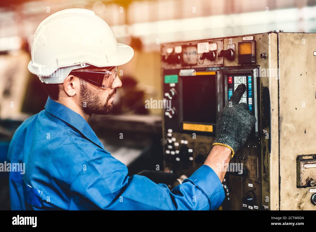 Travailleur latino-hispanique travaillant avec des machines dans une usine de l'industrie lourde, programmation CNC. Banque D'Images
