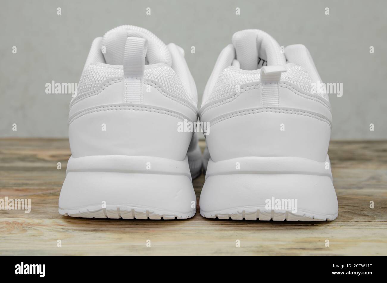 Magnifique paire de nouvelles sneakers blanches pour femme sur fond en bois pour un gros plan. Partie talon des baskets gros plan Banque D'Images