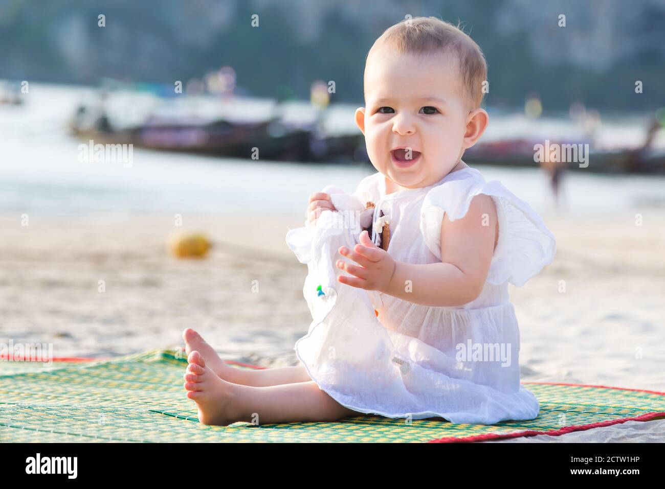 Crier bébé fille en robe blanche. Bébé assis sur la plage de sable tropical  Photo Stock - Alamy