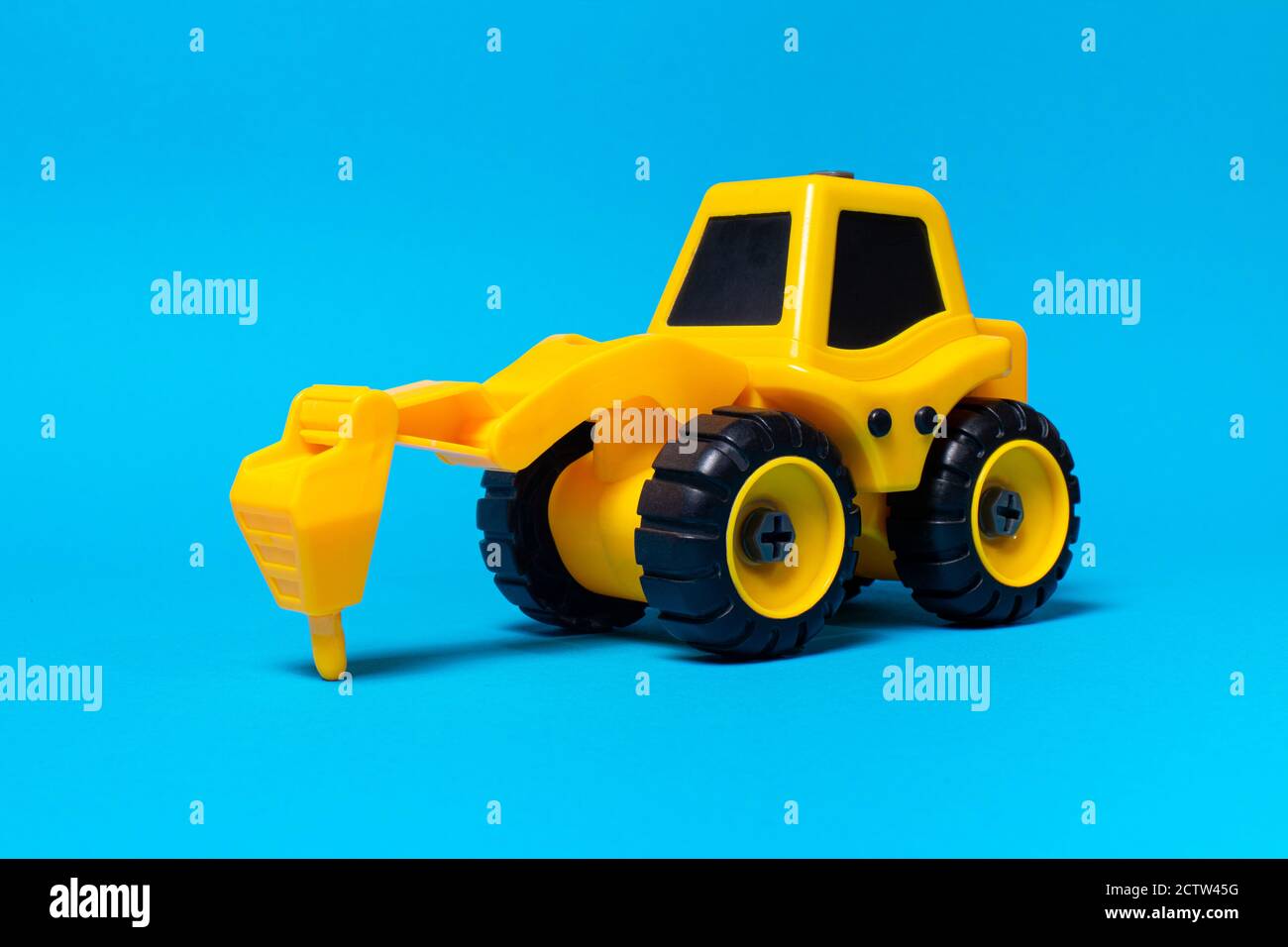 Jouet pour enfants, tracteur-semoir jaune sur fond bleu. Équipement de construction en plastique, magasin de jouets Banque D'Images