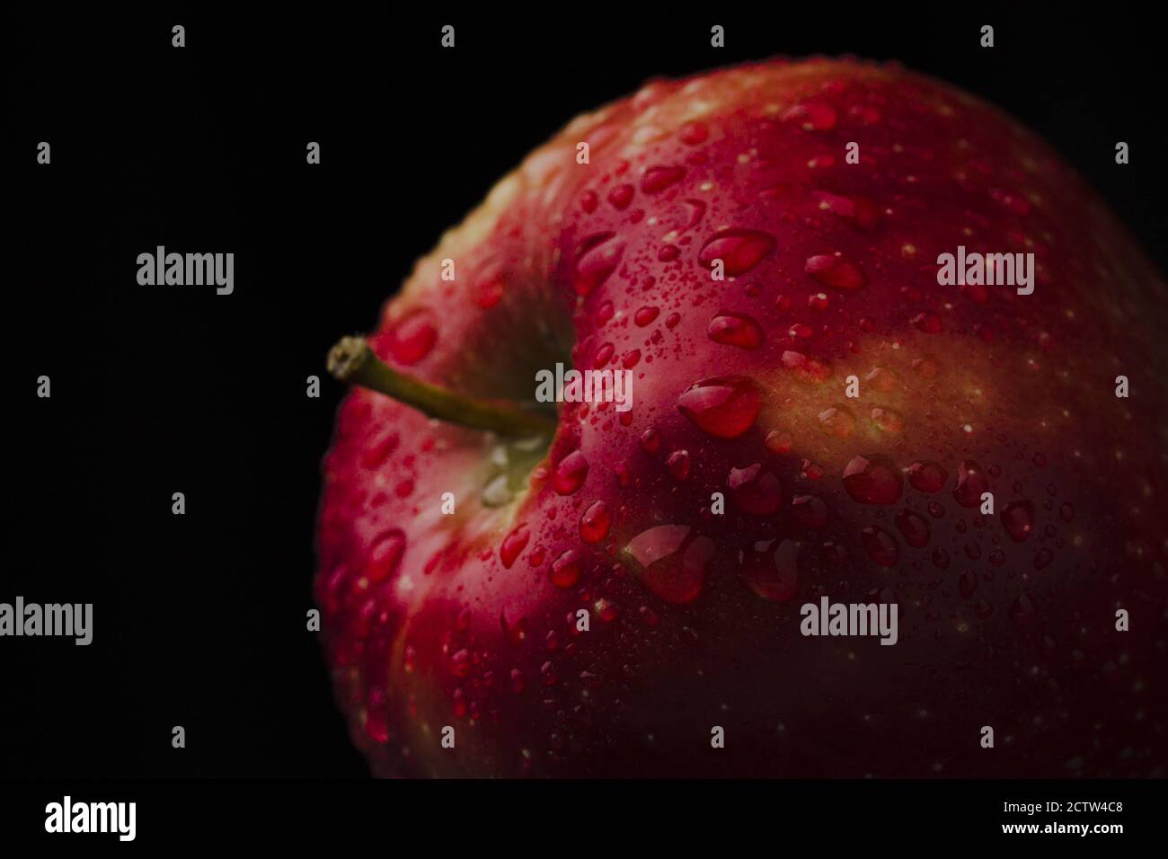 Pomme rouge et juteuse avec gouttes d'eau fond macro Banque D'Images