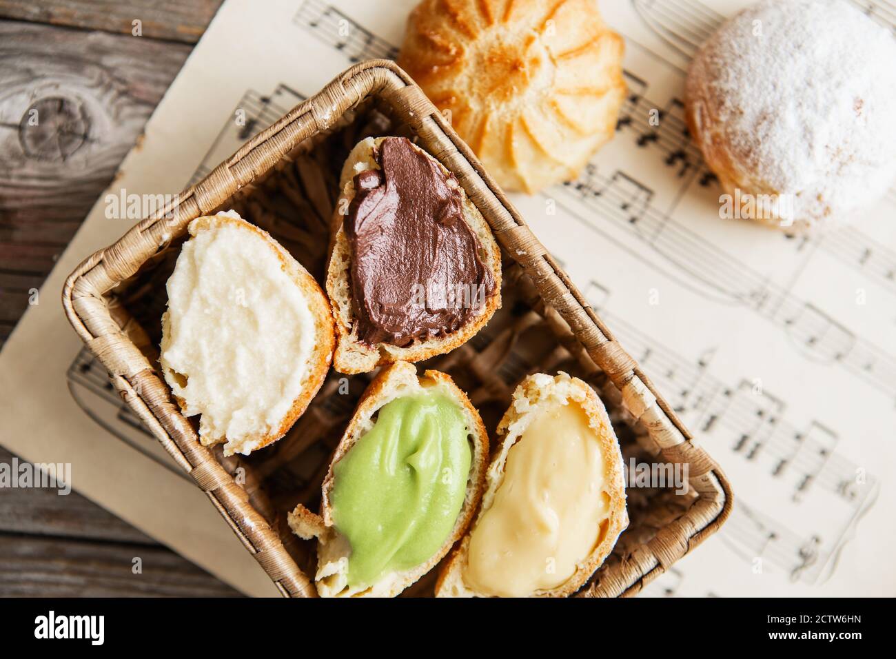 Profiteroles maison sur la feuille de musique avec des notes. Profiteroles (choux à la crème) - boulettes de pâte de choux françaises remplies de crème anglaise ou de fromage cottage Banque D'Images