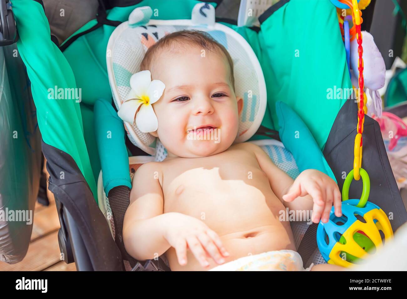 Petit Bebe A 8 Mois Avec Une Fleur De Frangipani Derriere L Oreille Se Trouve Dans Une Poussette De Voyage Et Profite Du Soleil Lors D Un Voyage En Asie Photo Stock Alamy