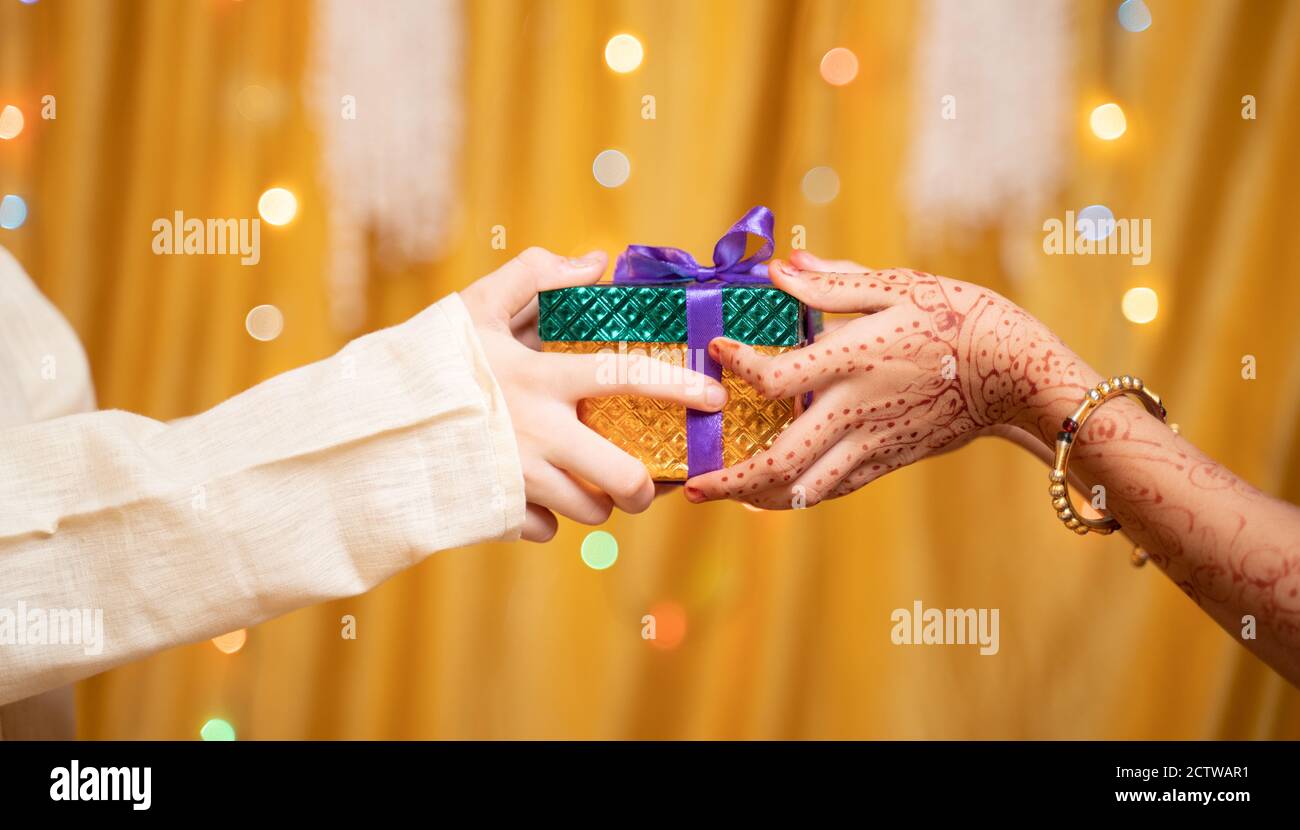Gros plan des mains de frère donnant cadeau à soeur pendant raksha Bandhan, Bhai Dooj ou Bhaubeej festival religieux indien Banque D'Images Gros plan des mains de frère donnant cadeau à soeur pendant raksha Bandhan, Bhai Dooj ou Bhaubeej festival religieux indien Banque D'Images