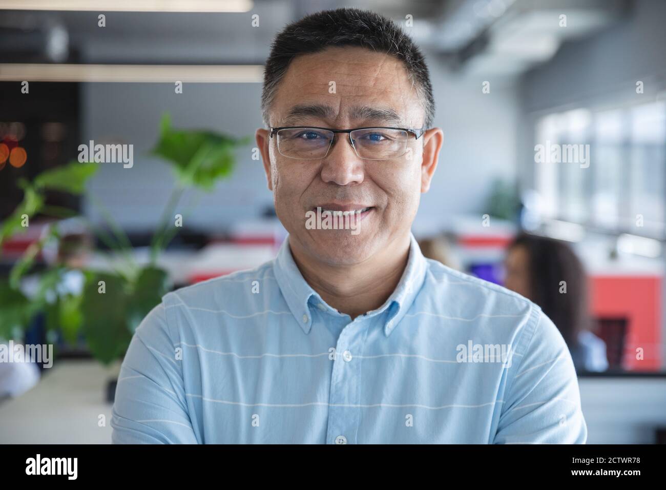 Portrait d'un homme d'affaires asiatique élégant habillé de manière décontractée avec des lunettes souriantes à l'appareil photo. Professionnel créatif travaillant dans un moderne Banque D'Images