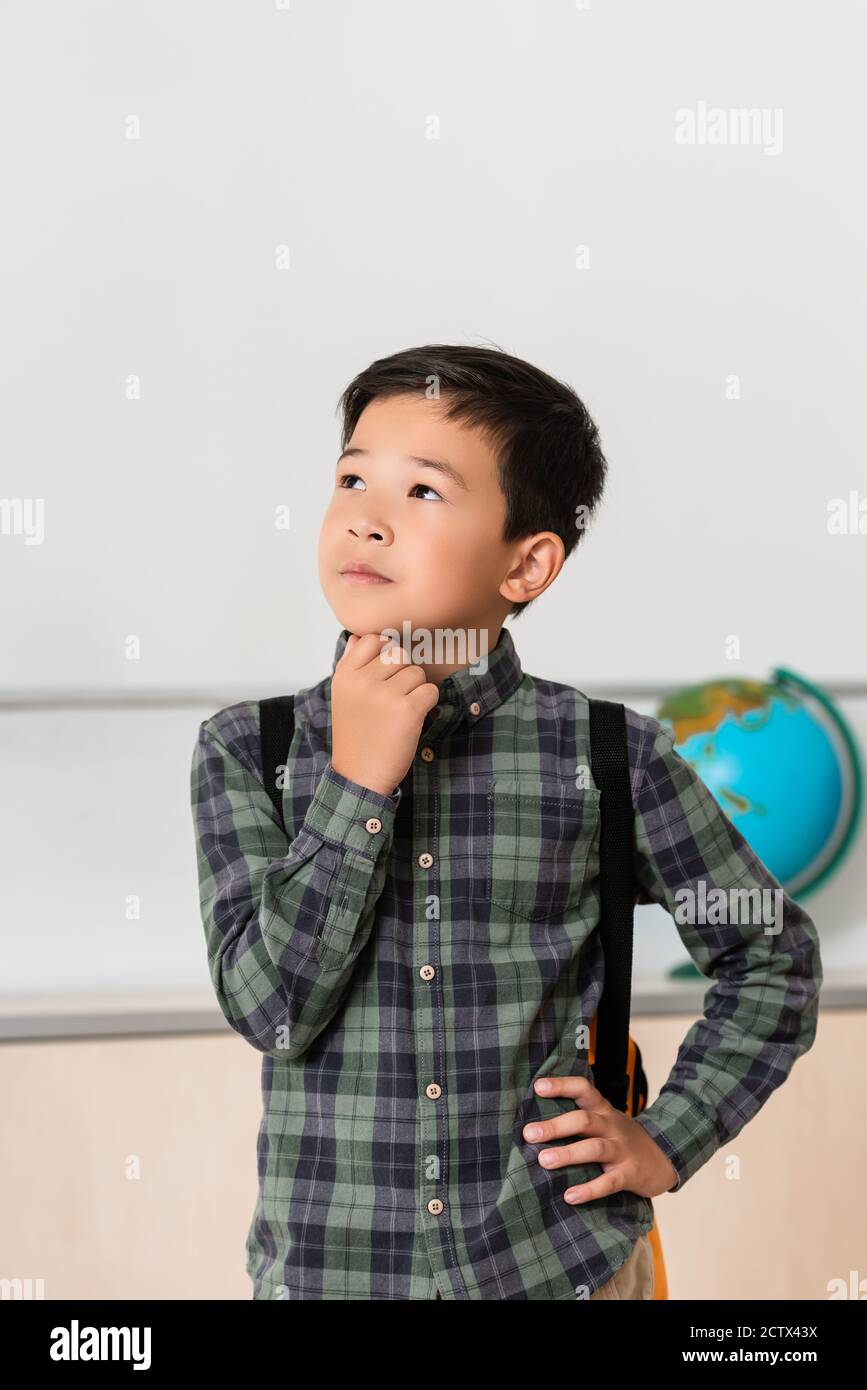 Lycéen asiatique bien pensé avec main sur la hanche en classe Banque D'Images