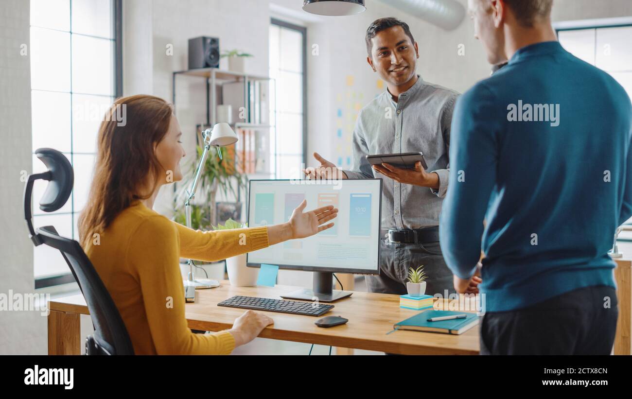 Trois développeurs de logiciels mobiles travaillent sur un ordinateur de bureau, ils discutent de la conception d'applications de smartphone utiliser la tablette numérique à écran tactile. Moderne et élégant Banque D'Images