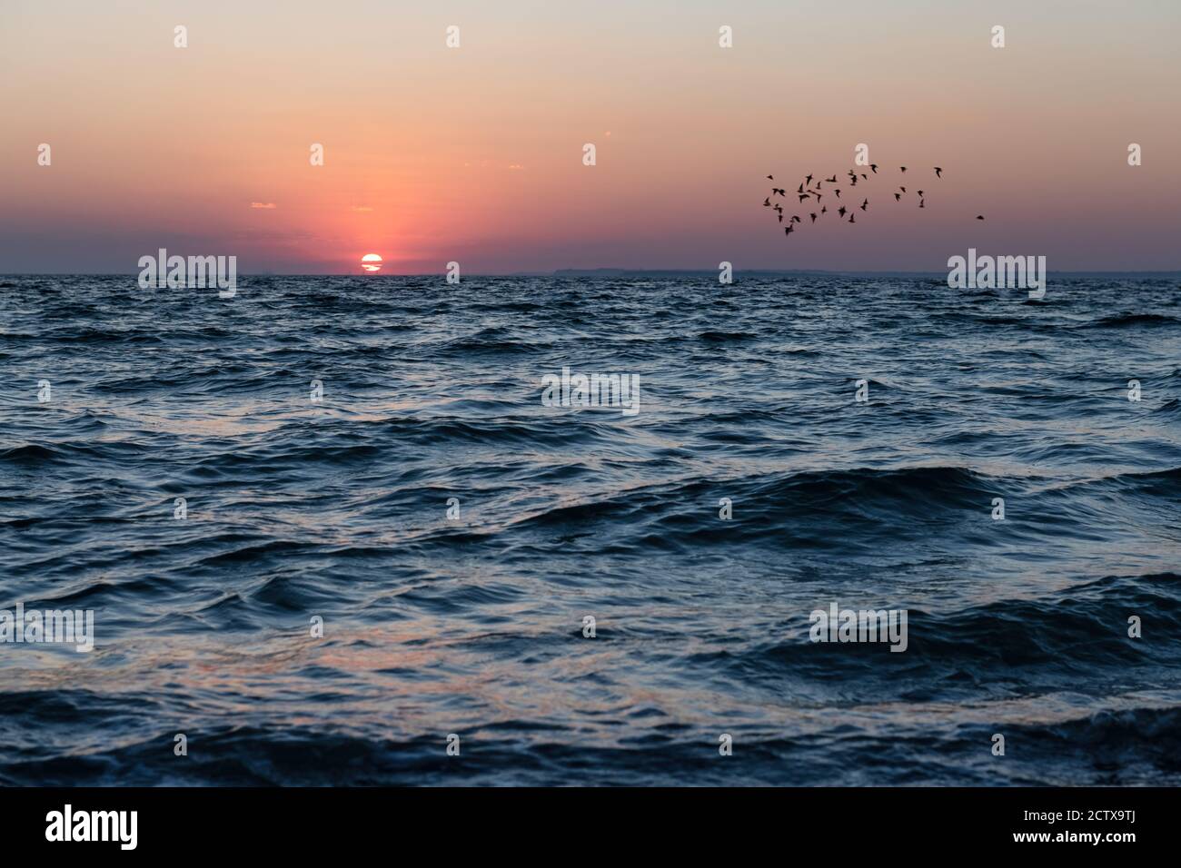 Coucher de soleil dans l'océan avec grand soleil crépuscule vagues douces et ciel nuageux rouge. Fond du lever du soleil de la mer. Photographie de paysage Banque D'Images