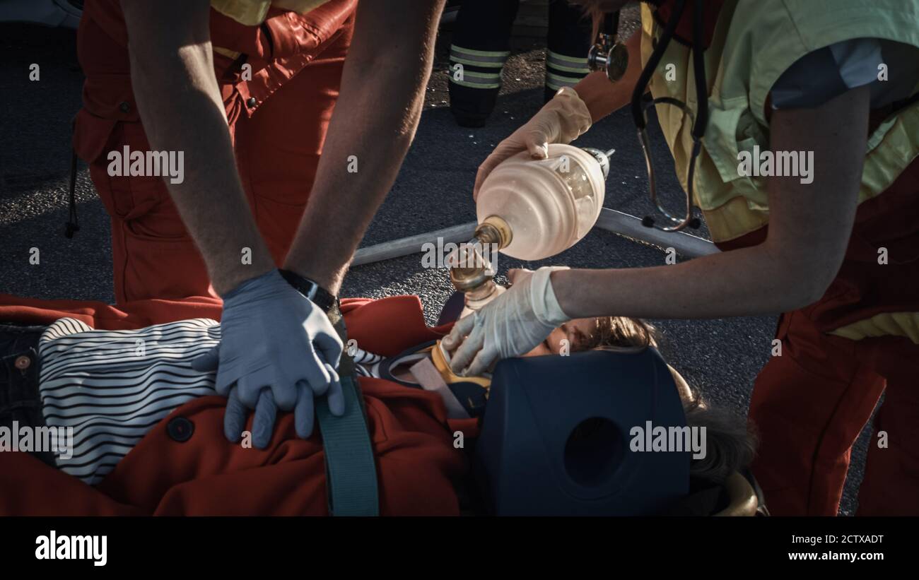 Sur la scène d'accident de la circulation automobile : les ambulanciers paramédicaux sauvant la vie d'une victime femelle qui est allongé sur des brancards. Ils appliquent le masque d'oxygène, font Banque D'Images