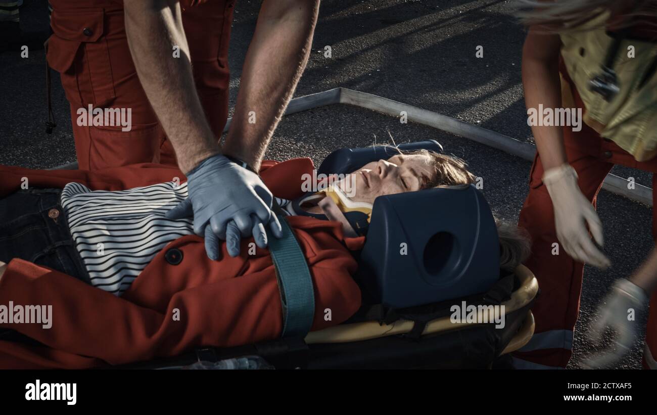 Sur la scène d'accident de la circulation automobile : les ambulanciers paramédicaux sauvant la vie d'une victime femelle qui est allongé sur des brancards. Ils appliquent le masque d'oxygène, font Banque D'Images
