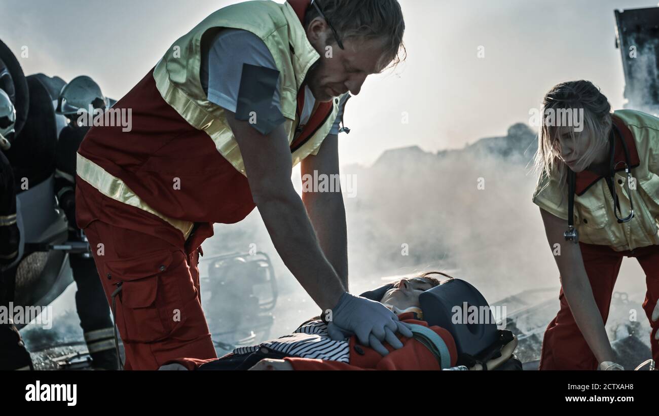 Sur la scène d'accident de la circulation automobile : les ambulanciers paramédicaux sauvant la vie d'une victime femelle qui est allongé sur des brancards. Ils appliquent le masque d'oxygène, font Banque D'Images