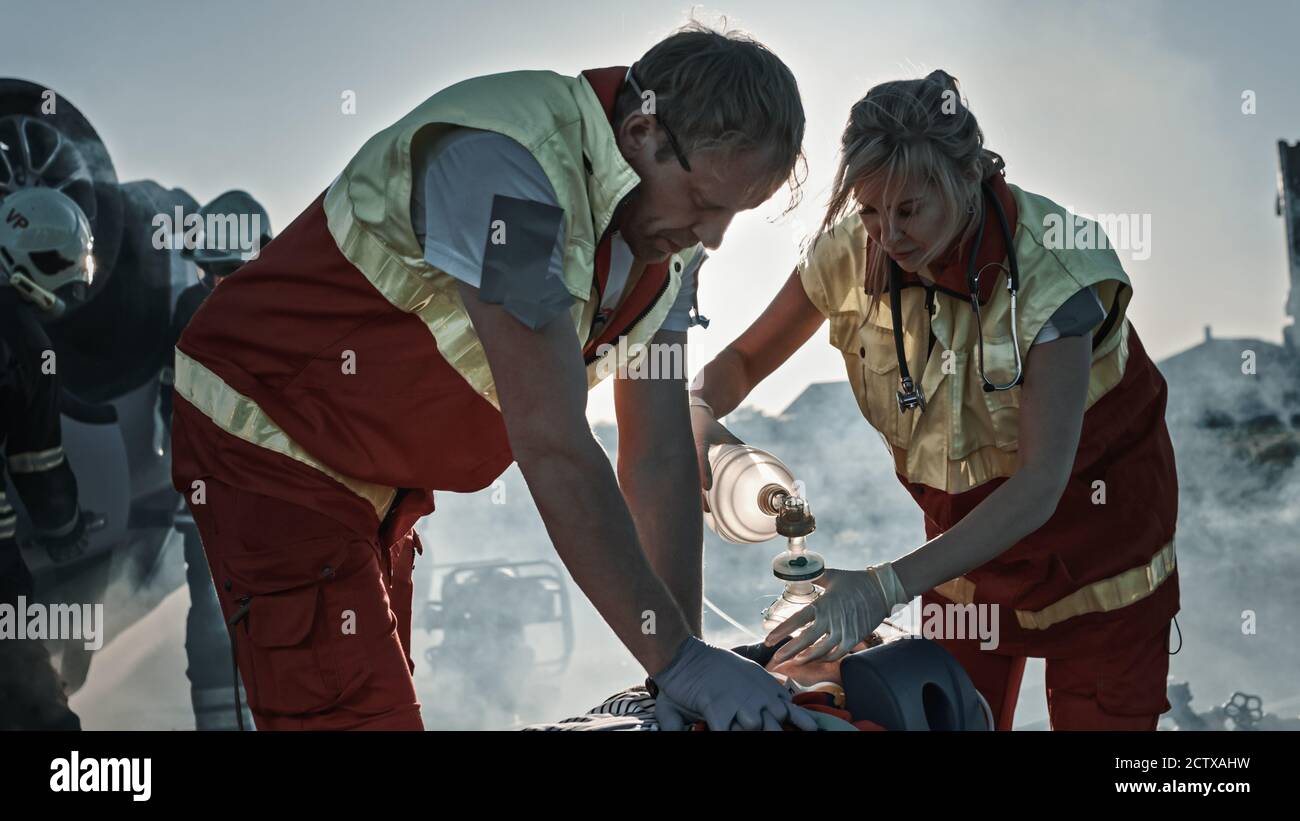 Sur la scène d'accident de la circulation automobile : les ambulanciers paramédicaux sauvant la vie d'une victime femelle qui est allongé sur des brancards. Ils appliquent le masque d'oxygène, font Banque D'Images