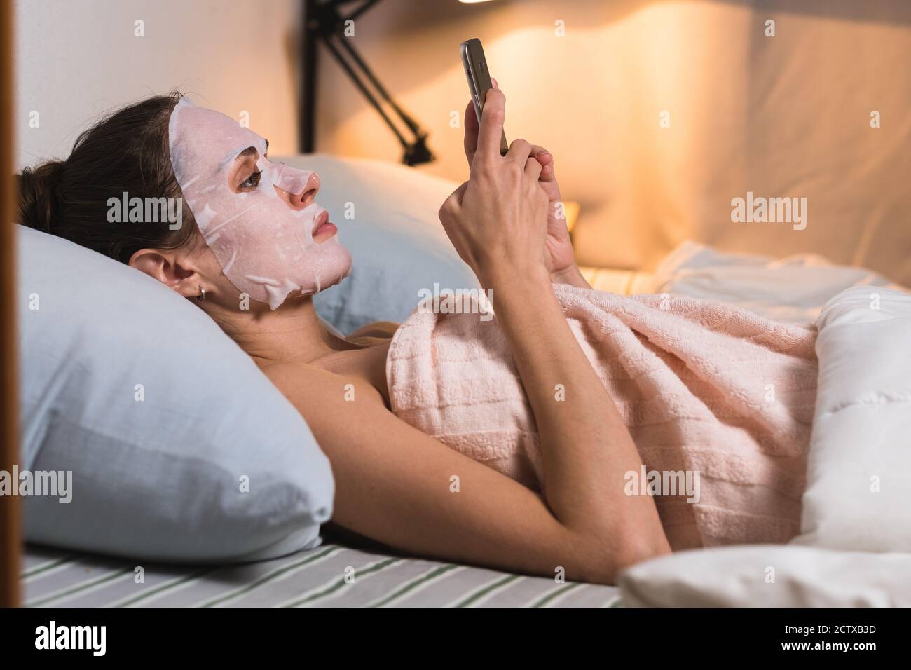Femme soins de la peau procédure cosmétique naviguez téléphone. Banque D'Images