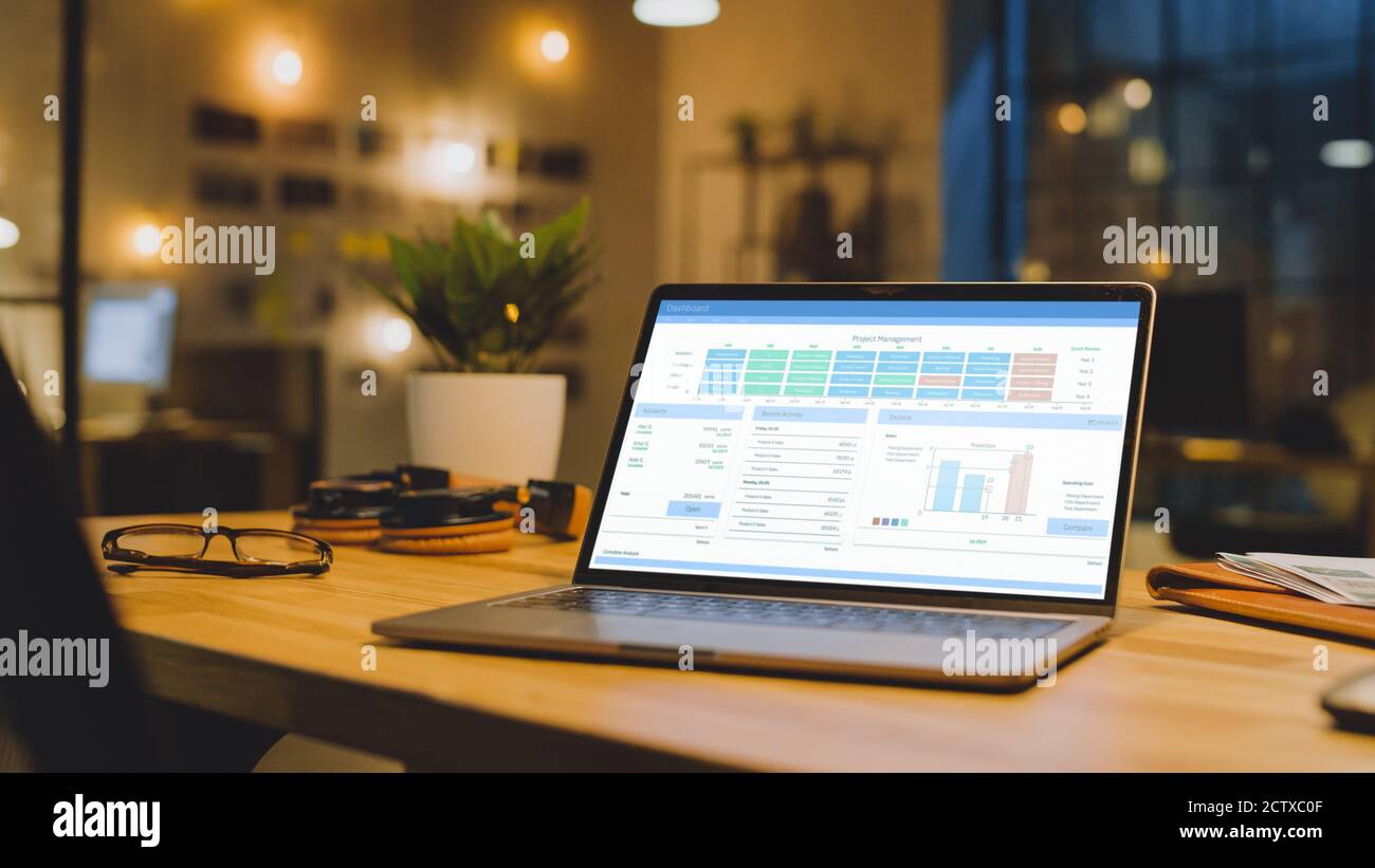 L'ordinateur portable du bureau affiche les données de croissance de l'entreprise avec des graphiques, des graphiques et une interface utilisateur logicielle. En arrière-plan élégant et moderne Office Studio dans le Banque D'Images