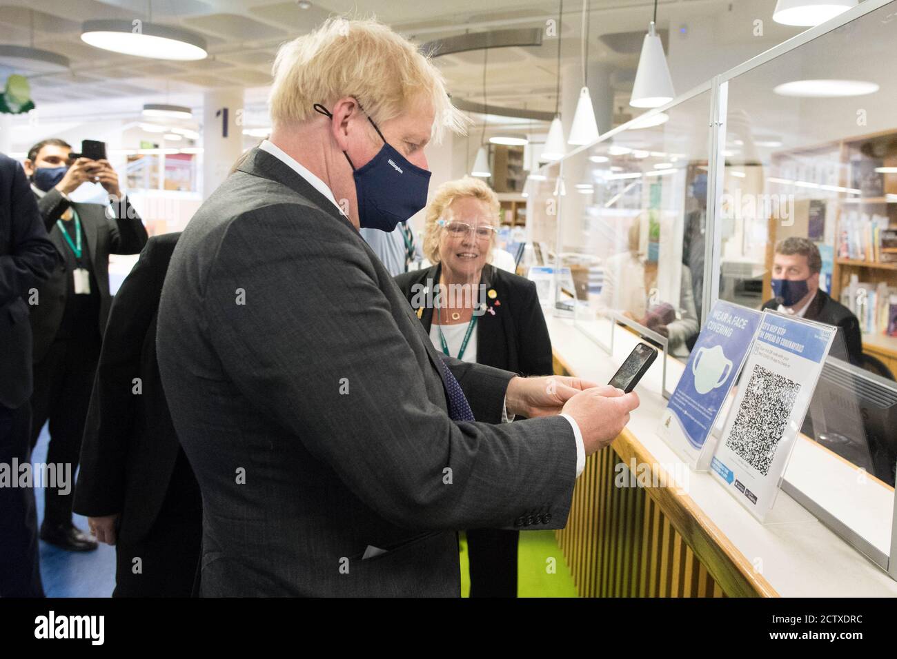 Le Premier ministre Boris Johnson scanne son application du coronavirus NHS à la bibliothèque Uxbridge lors d'une visite où il a rencontré des acheteurs et des commerçants dans sa circonscription d'Uxbridge, à l'ouest de Londres. Banque D'Images