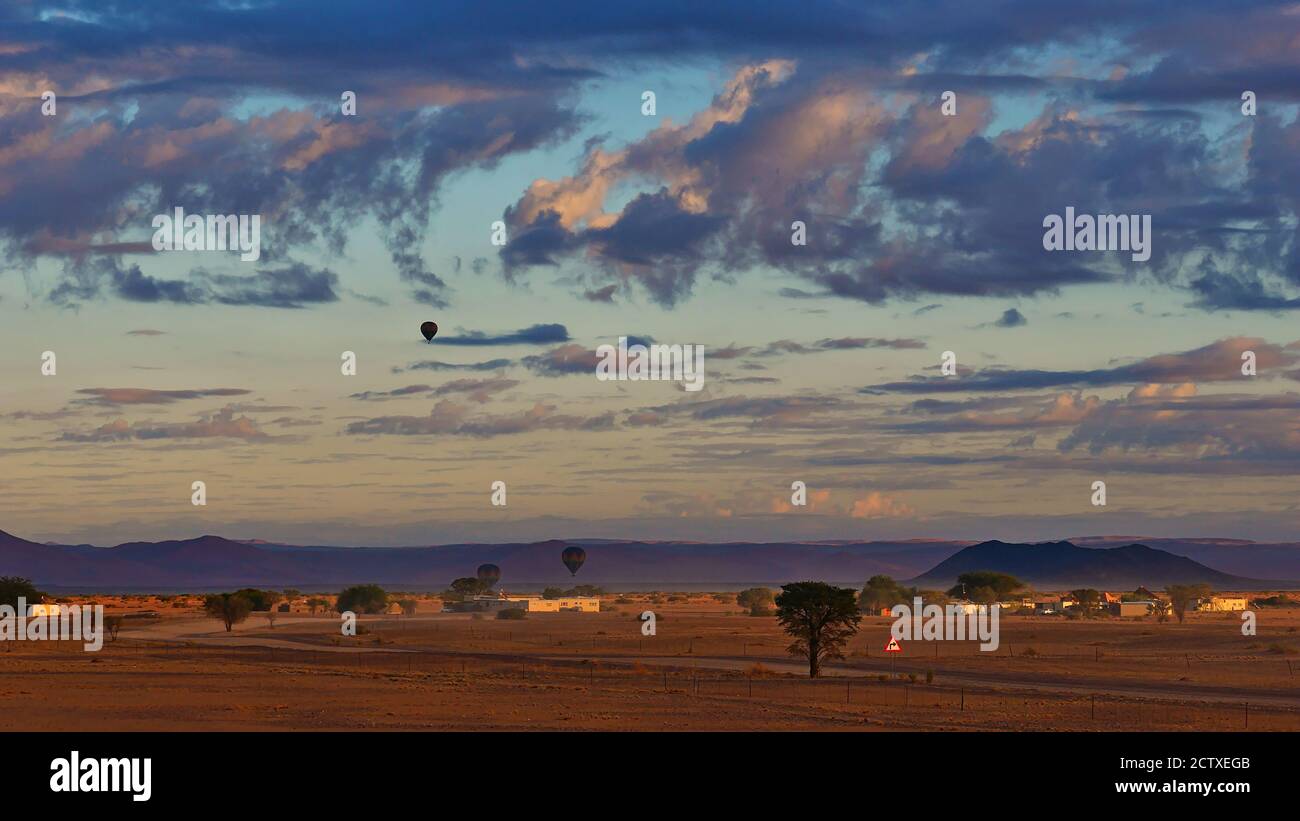 Des ballons à air chaud se détachent pour une aventure avant le coucher du soleil dans le désert du Namib près de Sesriem, Namibie, Afrique avec un beau ciel nuageux. Banque D'Images