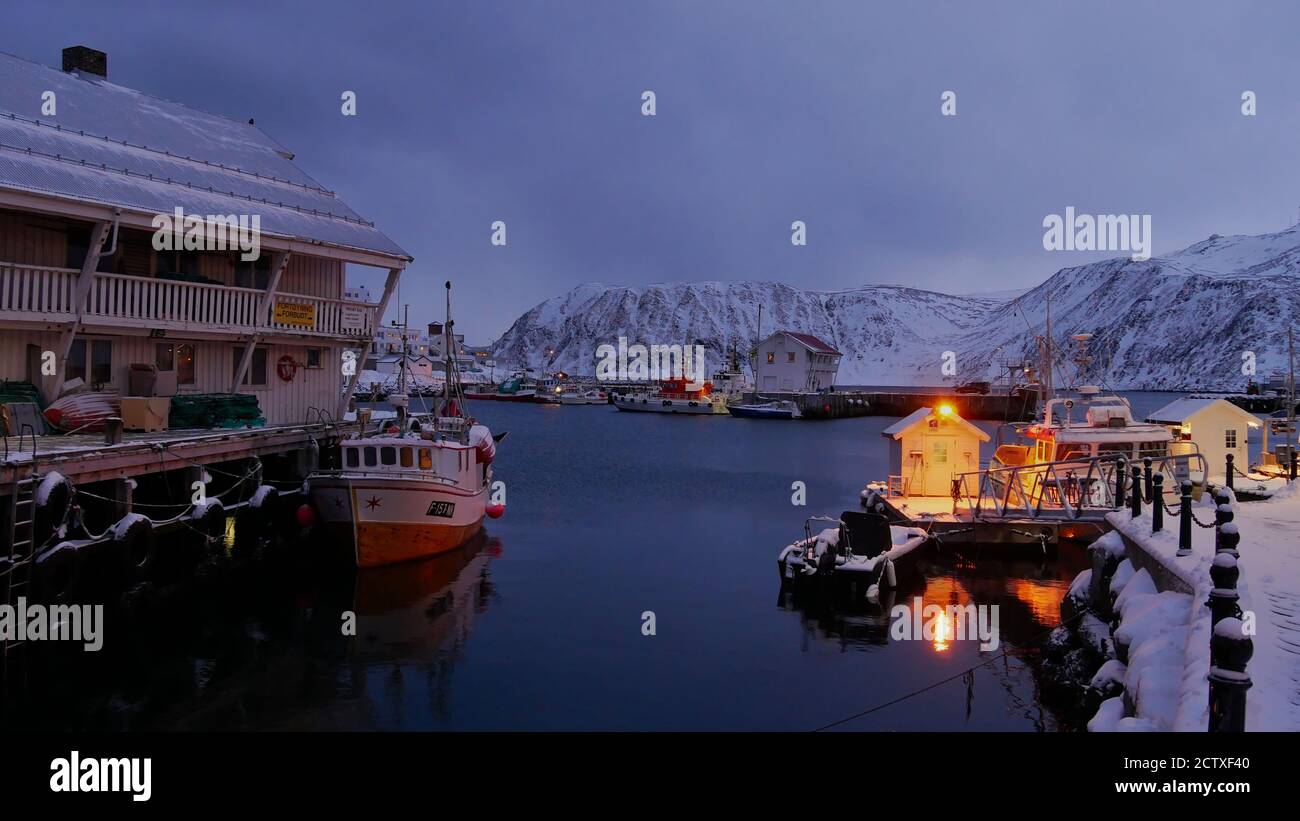 Photo de l'heure bleue avant la tombée de la nuit du port illuminé avec des bateaux de pêche à Honningsvag, Norvège, en hiver. Banque D'Images