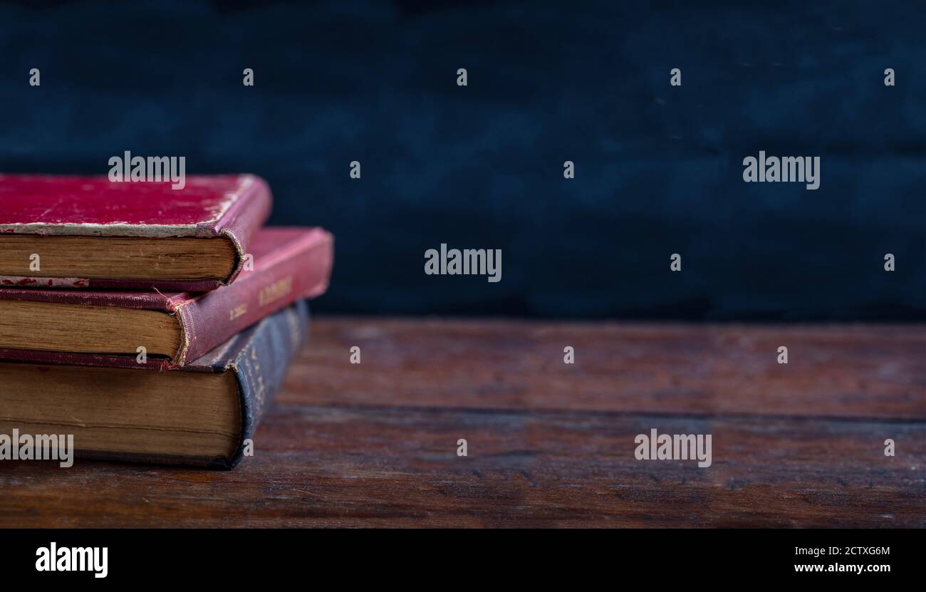 Bibliothèque d'époque, bureau de lecture, modèle. Les vieux livres sont empilés sur une table en bois, sur fond de tableau noir. Banque D'Images